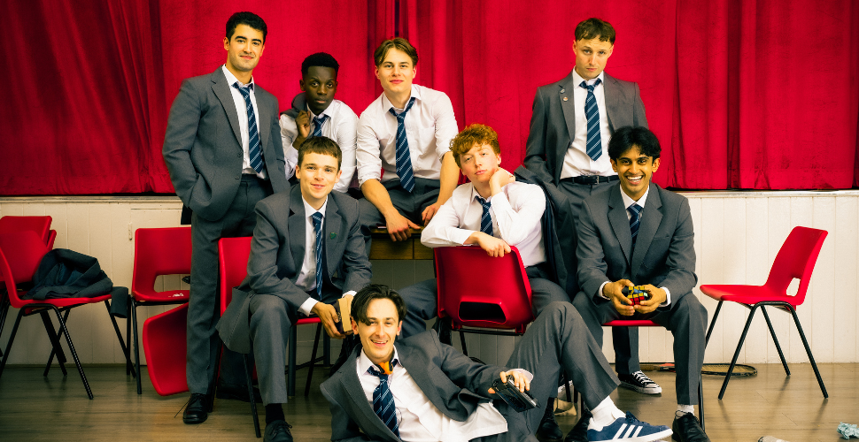 History boys cast in front of a stage and a red curtain